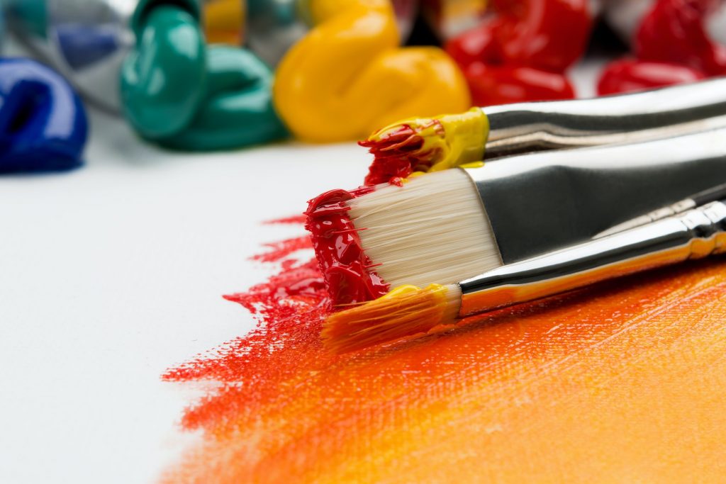 A set of paint brushes with red and orange paint on them