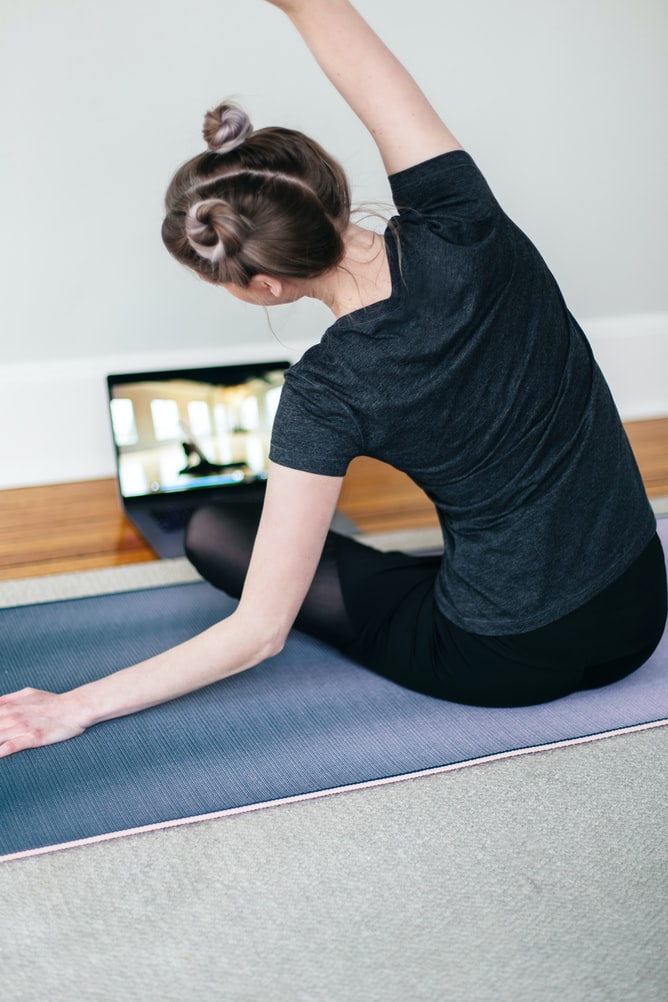 woman on yoga mat doing a virtual fitness lesson