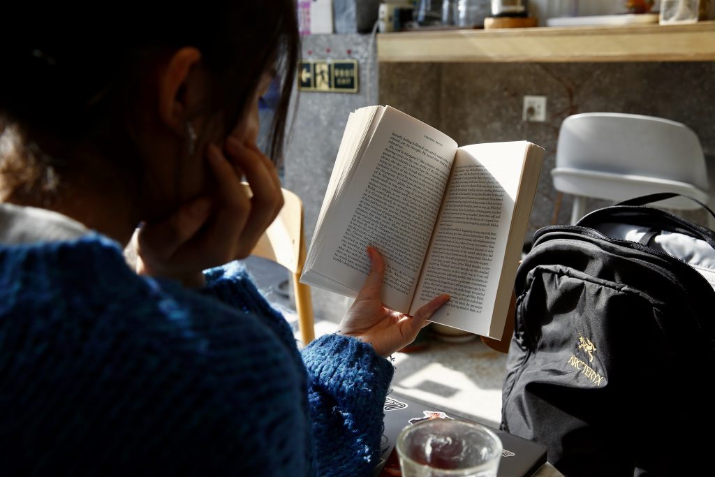 woman in blue sweater reading book