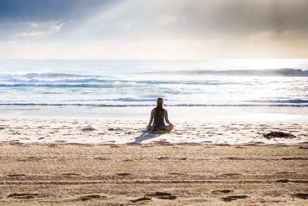woman on beach meditating